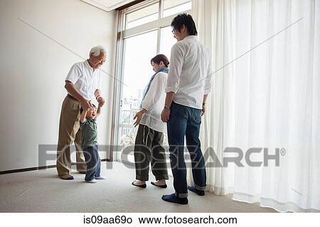 Picture - Three generation family standing by window. Fotosearch
