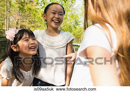 Stock Image - Three girls talking and laughing. Fotosearch