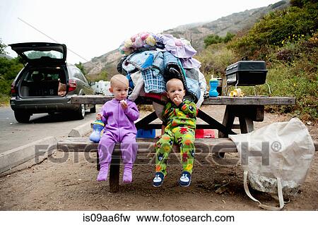 Toddler twins eating banana on picnic bench View Large Photo Image Stock Photo - Toddler twins eating banana on picnic bench. Fotosearch