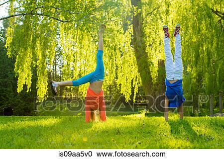 Two girls doing handstands in park View Large Photo Image Stock Image - Two girls doing handstands in park. Fotosearch