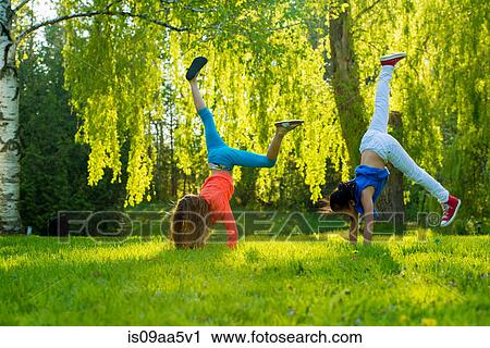 Two girls doing handstands in park View Large Photo Image Stock Image - Two girls doing handstands in park. Fotosearch
