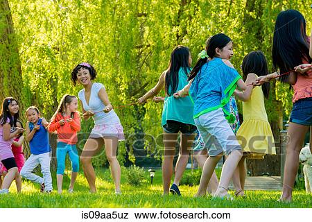 Woman and group of girls doing tug of war in park View Large Photo Image Stock Photo - Woman and group of girls doing tug of war in park. Fotosearch