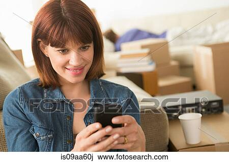 Stock Image - Woman texting on cellphone whilst moving house. Fotosearch