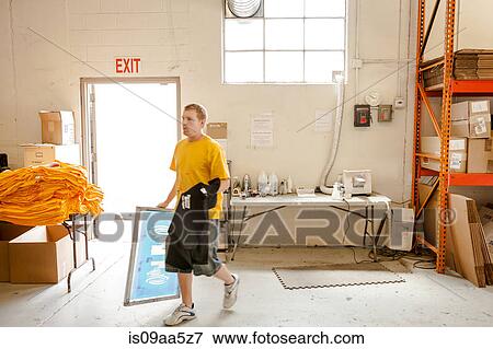 Stock Photo - Worker carrying frame and t-shirt in screen printing workshop. Fotosearch