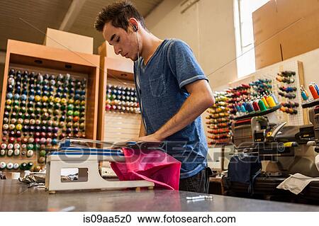 Stock Image - Worker using embroidery machine in t-shirt printing workshop. Fotosearch