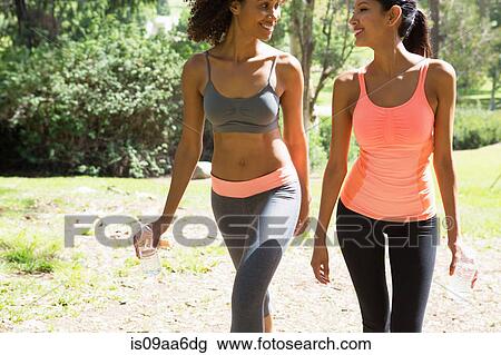 Stock Image - Young and mid adult woman walking through park. Fotosearch
