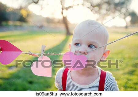 Young boy looking over heart shapes on washing line View Large Photo Image Stock Photograph - Young boy looking over heart shapes on washing line. Fotosearch