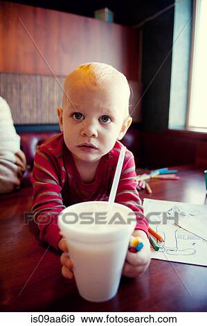 Stock Photo - Young boy reaching for milkshake in cafe. Fotosearch