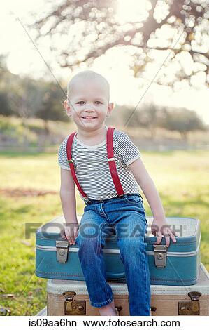 Young boy sitting on suitcases outdoors, portrait View Large Photo Image Picture - Young boy sitting on suitcases outdoors, portrait. Fotosearch