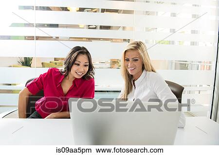 Picture - Young business colleagues looking at laptop in conference room. Fotosearch