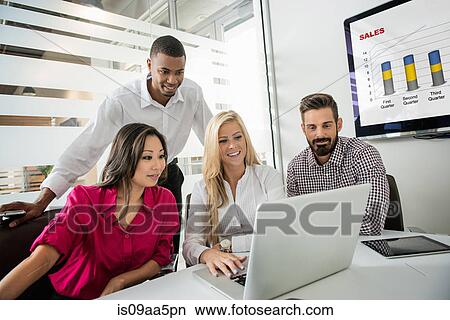 Picture - Young business colleagues looking at laptop in conference room. Fotosearch