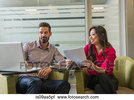 Stock Image - Young business colleagues looking at laptop meeting. Fotosearch