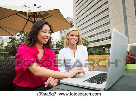 Stock Photo - Young business colleagues looking at laptop. Fotosearch