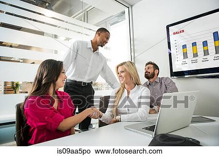 Picture - Young business colleagues shaking hands in conference room. Fotosearch