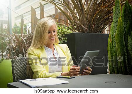 Stock Photography - Young businesswoman looking at digital tablet at table. Fotosearch