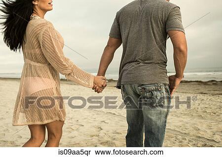 Stock Photography - Young couple holding hands on beach. Fotosearch