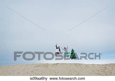 Stock Photo - Young couple leaping on beach. Fotosearch