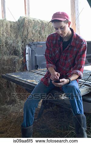 Young farmer sitting and using mobile phone View Large Photo Image Stock Photography - Young farmer sitting and using mobile phone. Fotosearch
