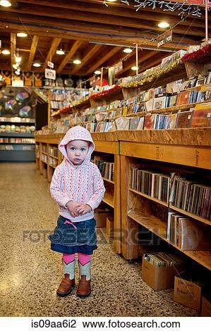 Stock Image - Young girl standing in store, portrait. Fotosearch