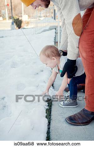 Young girl touching snow with father watching View Large Photo Image Stock Photo - Young girl touching snow with father watching. Fotosearch