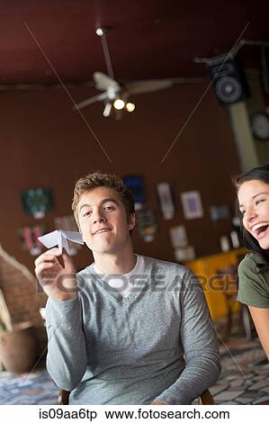 Stock Photography - Young man holding paper airplane in coffee house. Fotosearch