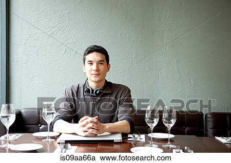 Stock Image - Young man in restaurant, portrait. Fotosearch