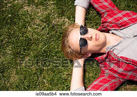 Picture - Young man lying down in park. Fotosearch