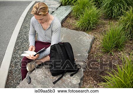 Young man studying text book in park View Large Photo Image Stock Image - Young man studying text book in park. Fotosearch