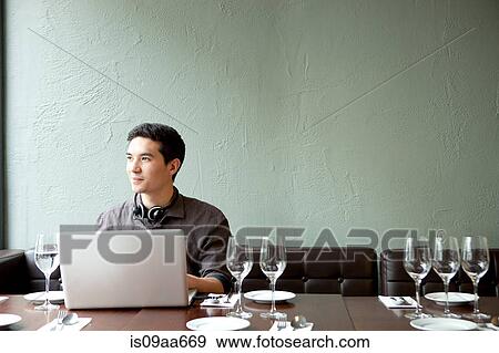 Young man using laptop in restaurant View Large Photo Image Stock Photo - Young man using laptop in restaurant. Fotosearch