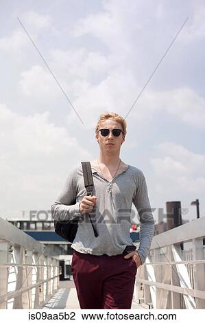 Stock Image - Young man walking over footbridge, Brooklyn, New York City, USA. Fotosearch