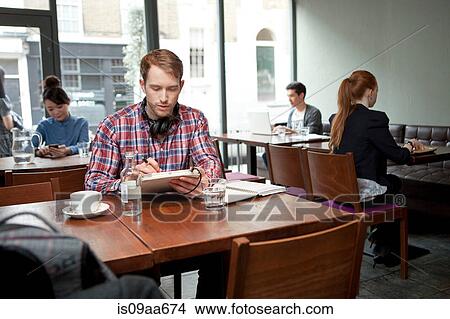 Young man with digital tablet in cafe View Large Photo Image Picture - Young man with digital tablet in cafe. Fotosearch