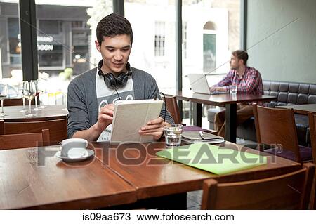 Young man with digital tablet in cafe View Large Photo Image Stock Image - Young man with digital tablet in cafe. Fotosearch