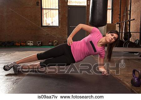 Young woman exercising on mat in gym View Large Photo Image Stock Photo - Young woman exercising on mat in gym. Fotosearch