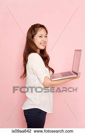 Young woman holding laptop, portrait View Large Photo Image Stock Image - Young woman holding laptop, portrait. Fotosearch