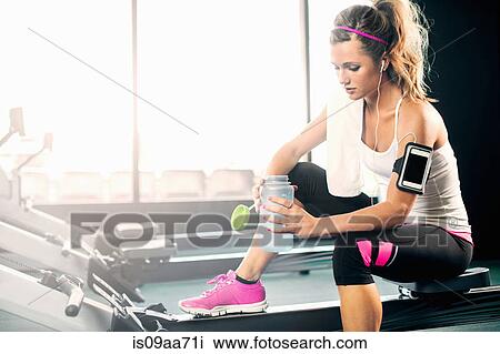 Young woman holding water bottle in gym View Large Photo Image Stock Image - Young woman holding water bottle in gym. Fotosearch
