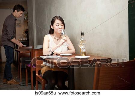 Stock Photograph - Young woman holding wine glass in restaurant. Fotosearch