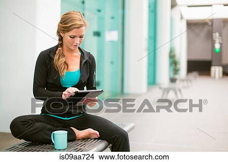 Picture - Young woman in gym corridor using digital tablet. Fotosearch