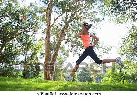 Young woman jogging through park View Large Photo Image Stock Image - Young woman jogging through park. Fotosearch