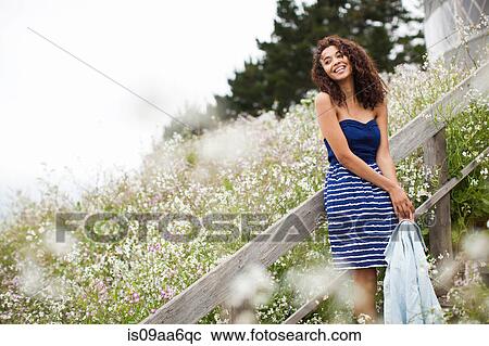 Stock Image - Young woman laughing by meadow. Fotosearch