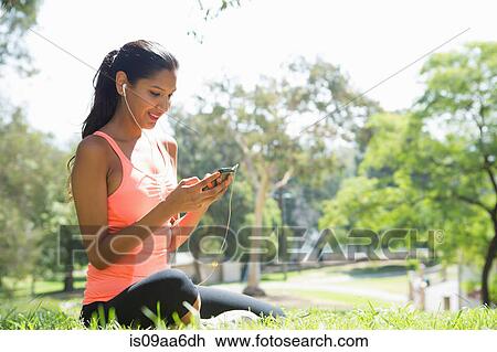 Young woman listening to mp3 player in park View Large Photo Image Stock Image - Young woman listening to mp3 player in park. Fotosearch