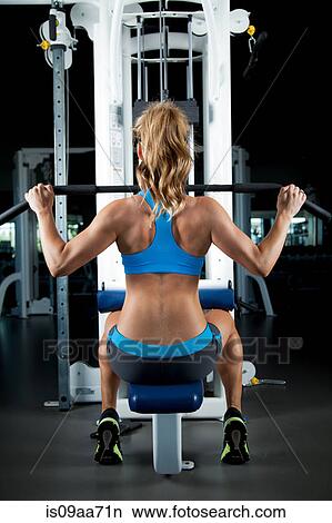 Picture - Young woman pulling weights. Fotosearch