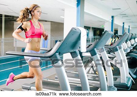Stock Image - Young woman running on treadmill. Fotosearch