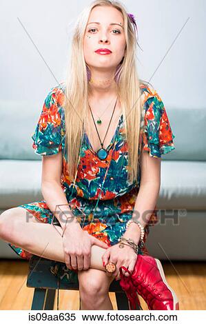 Stock Photography - Young woman sitting in floral patterned dress, portrait. Fotosearch