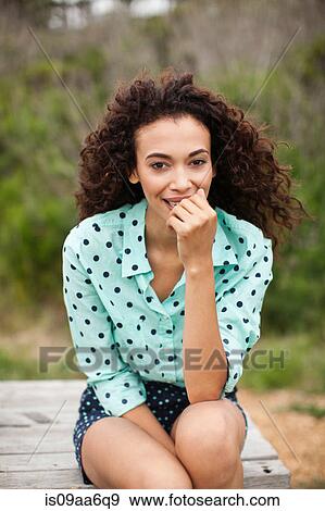 Young woman sitting on picnic table smiling, portrait View Large Photo Image Stock Photo - Young woman sitting on picnic table smiling, portrait. Fotosearch