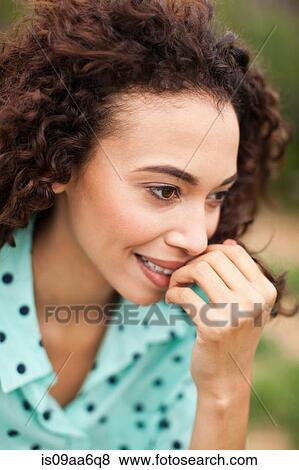 Stock Photo - Young woman smiling with hand on chin, close up. Fotosearch