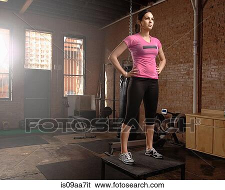 Stock Photograph - Young woman standing on table in gym. Fotosearch
