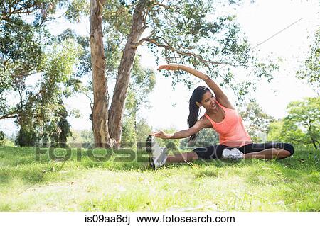 Stock Image - Young woman stretching in park. Fotosearch