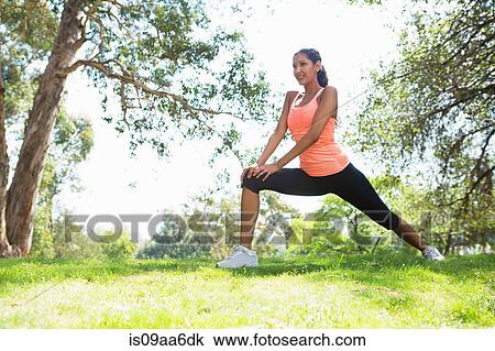 Stock Image - Young woman stretching in park. Fotosearch