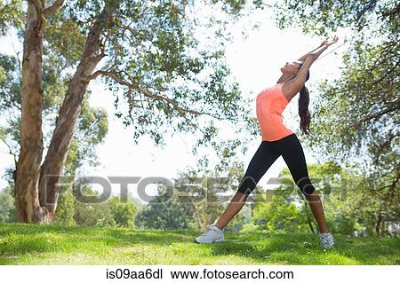 Stock Image - Young woman stretching in park. Fotosearch