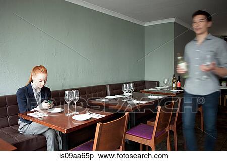 Young woman using cell phone in restaurant, waiter walking past View Large Photo Image Stock Photography - Young woman using cell phone in restaurant, waiter walking past. Fotosearch
